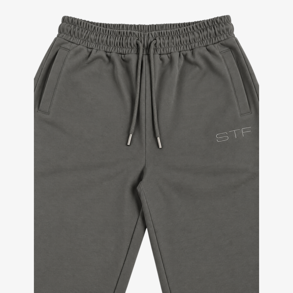 STF grey relaxed open-hem trousers — waistband and embroidery detail