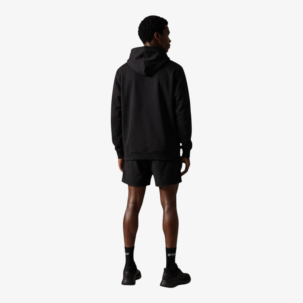 Back view of a man wearing a Seejthreadsflames (STF) black heavyweight cotton oversized hoodie and matching shorts.